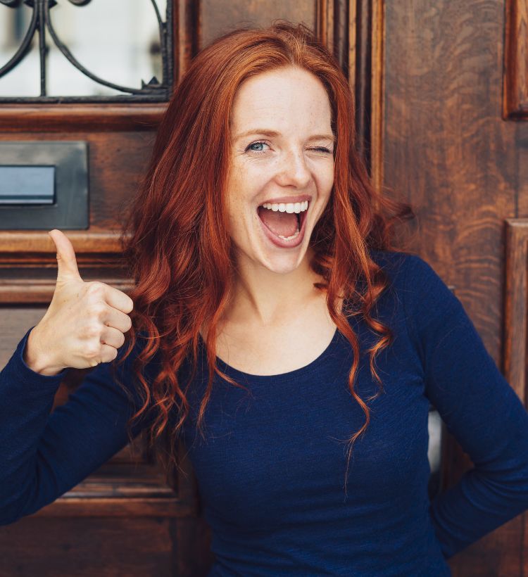 Lächelnde rothaarige Frau mit Sparschwein in der Hand
