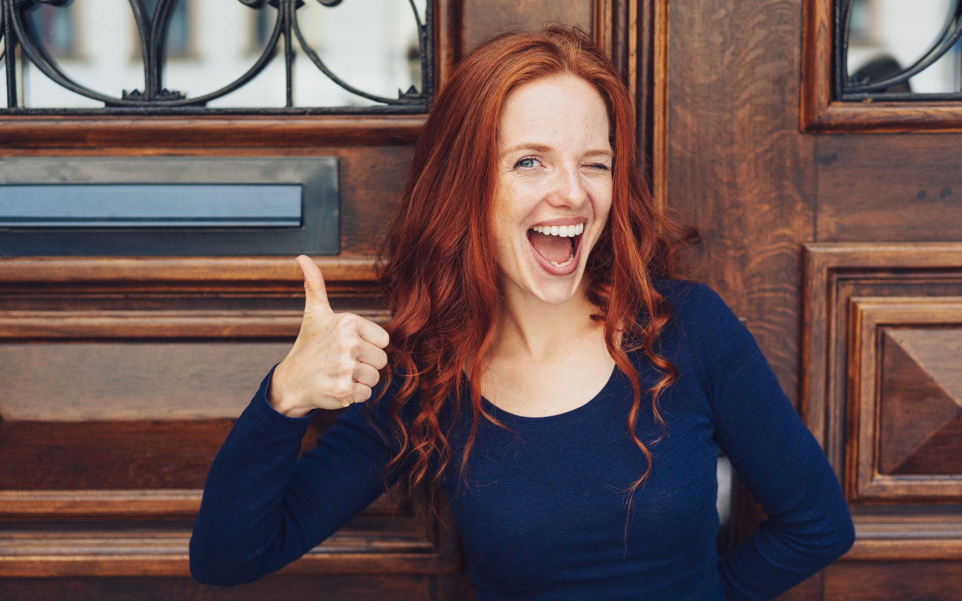 Lächelnde rothaarige Frau die den Daumen nach oben zeigt