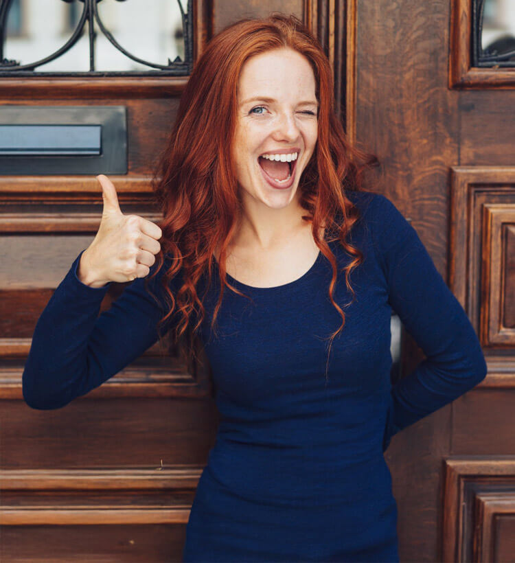 Lächelnde rothaarige Frau mit Sparschwein in der Hand